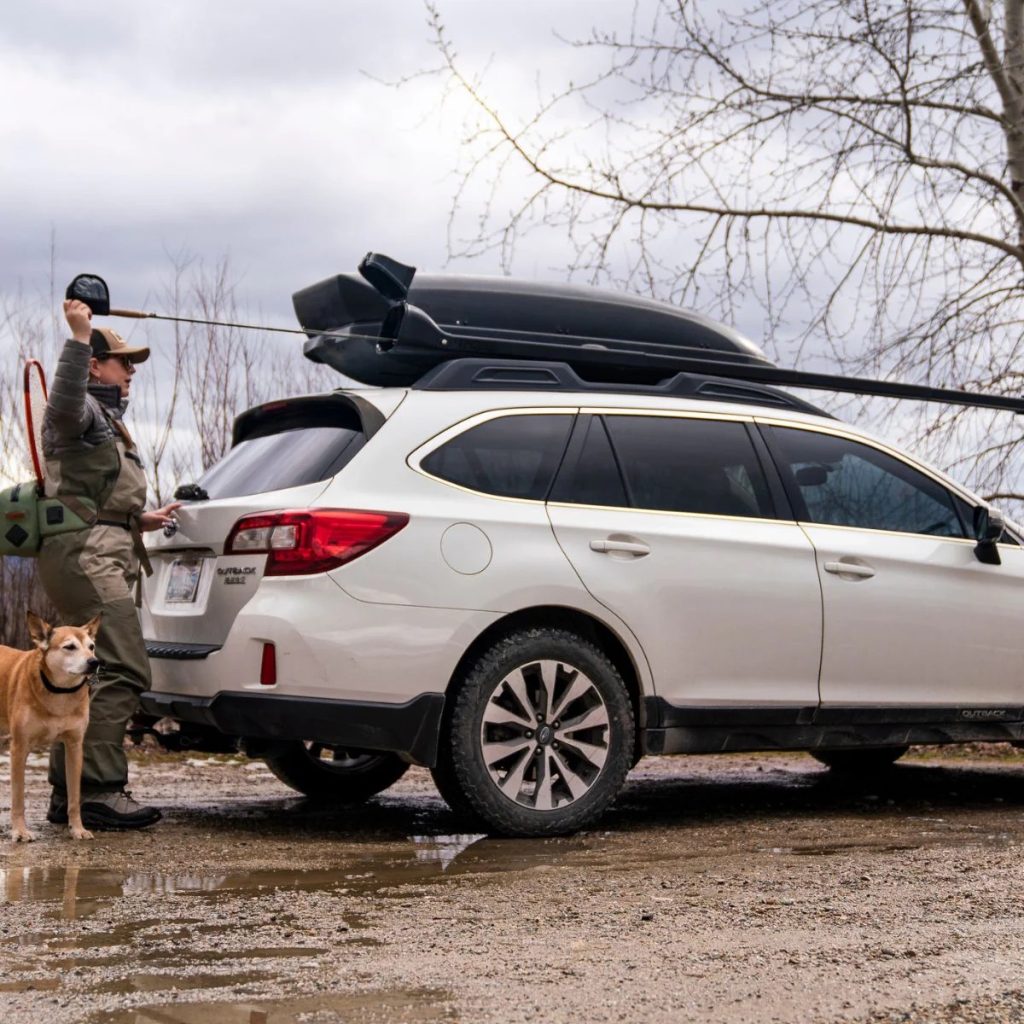 Trestle rod carrier on a car with angler feeding rod into it.